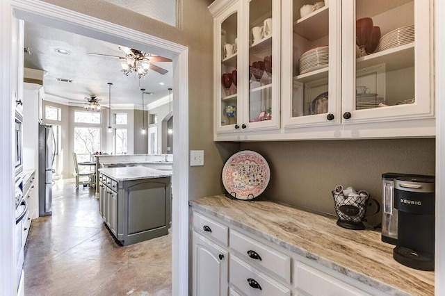 kitchen with white cabinets, appliances with stainless steel finishes, light stone countertops, and decorative light fixtures