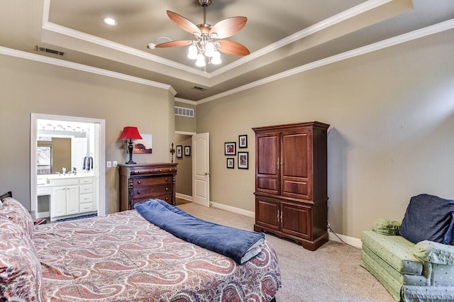 carpeted bedroom featuring a tray ceiling, ornamental molding, ensuite bathroom, and ceiling fan