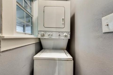 clothes washing area featuring stacked washer and clothes dryer