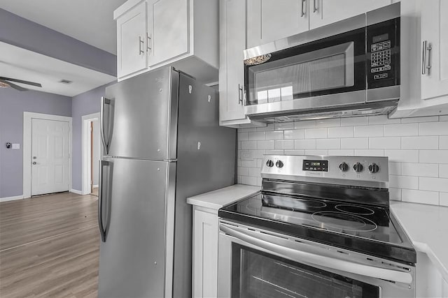 kitchen with appliances with stainless steel finishes, dark wood-type flooring, white cabinetry, and tasteful backsplash