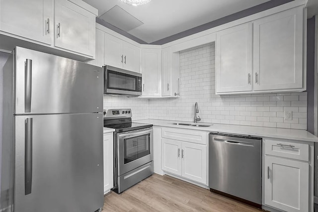 kitchen featuring appliances with stainless steel finishes, light hardwood / wood-style flooring, tasteful backsplash, sink, and white cabinetry