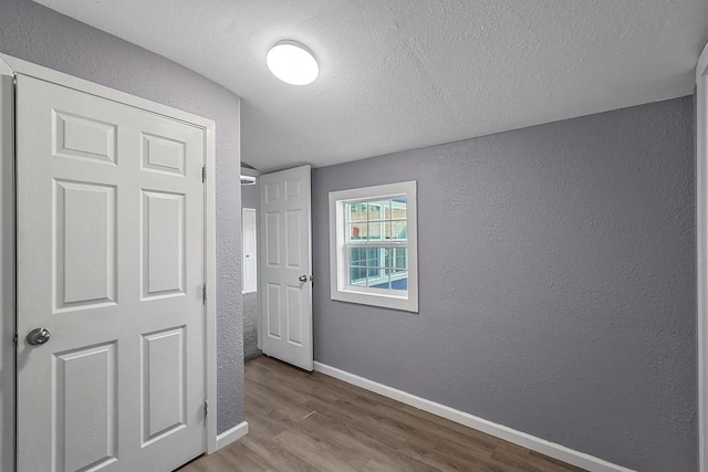 unfurnished bedroom with light wood-type flooring and a textured ceiling