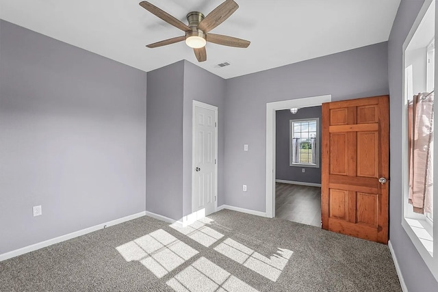 unfurnished bedroom with dark carpet and ceiling fan