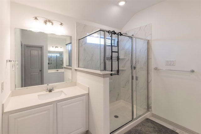 bathroom featuring a shower with door, vaulted ceiling, and vanity