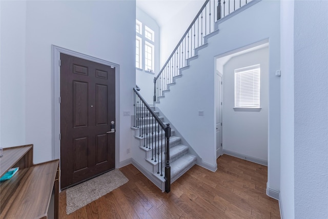 foyer entrance with plenty of natural light, dark wood-type flooring, and a towering ceiling