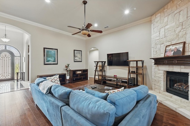 living room with a fireplace, arched walkways, dark wood-style flooring, and visible vents
