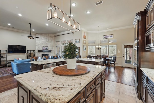 kitchen with open floor plan, visible vents, ceiling fan with notable chandelier, and a kitchen island