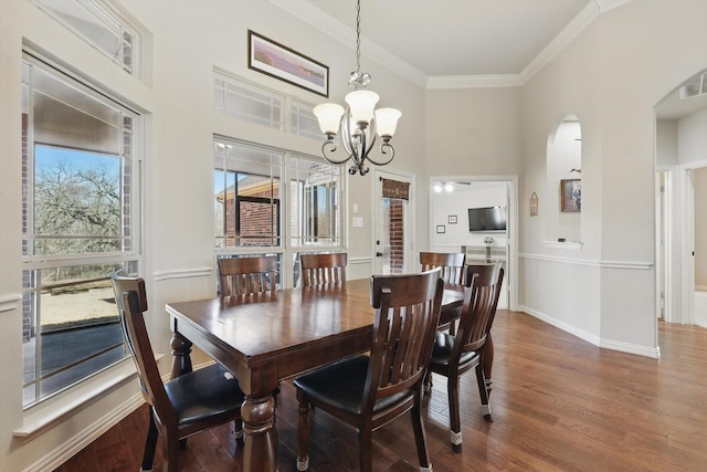 dining area with baseboards, arched walkways, a notable chandelier, crown molding, and wood finished floors