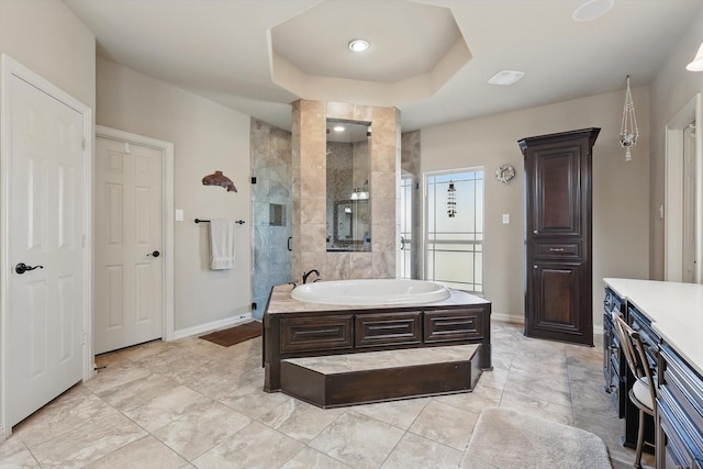 full bath with a bath, baseboards, a raised ceiling, and a stall shower