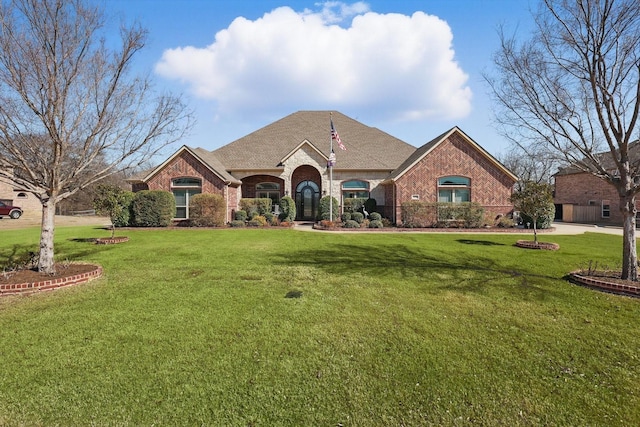 view of front of house featuring roof with shingles, a front yard, and brick siding
