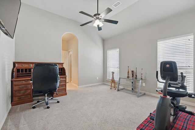 carpeted home office featuring ceiling fan, arched walkways, vaulted ceiling, visible vents, and baseboards