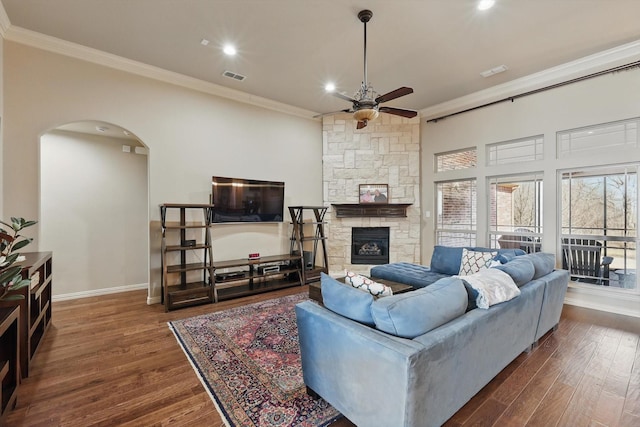 living area with visible vents, arched walkways, a ceiling fan, crown molding, and wood finished floors