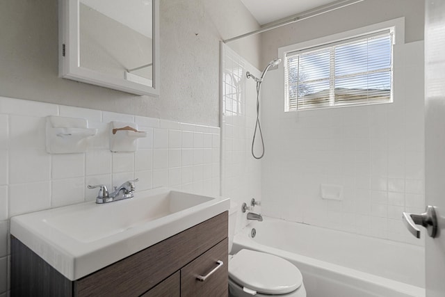 full bathroom featuring tiled shower / bath combo, toilet, tile walls, and vanity