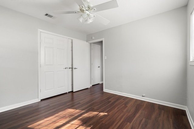 unfurnished bedroom with ceiling fan, a closet, and dark wood-type flooring