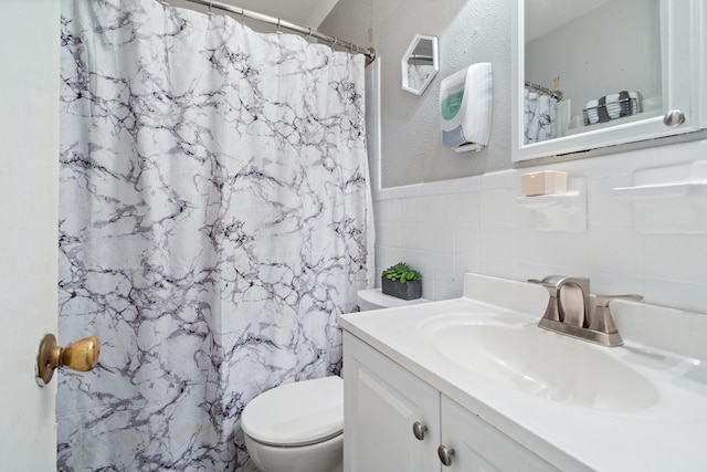 bathroom with tile walls, toilet, vanity, and walk in shower