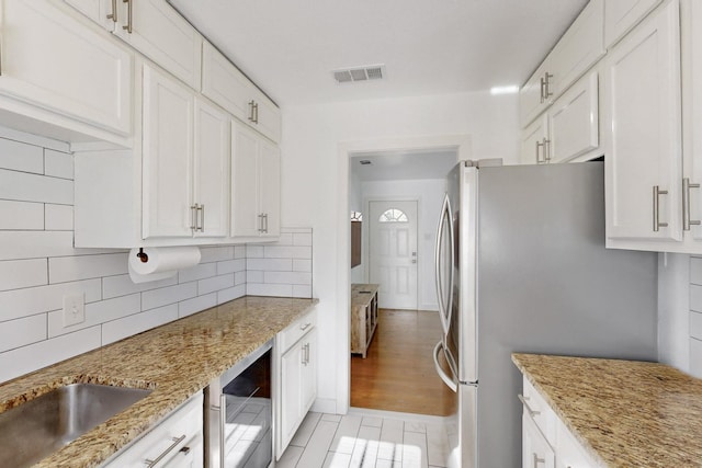 kitchen with white cabinetry, wine cooler, and light stone counters