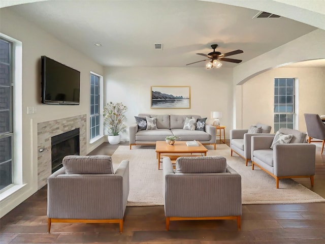 living area with arched walkways, visible vents, dark wood finished floors, and a fireplace