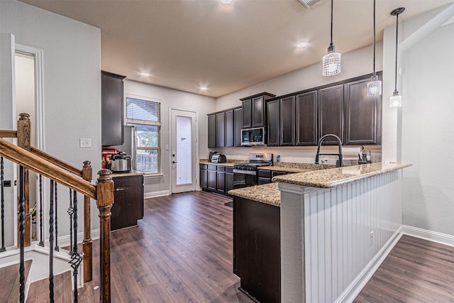 kitchen with kitchen peninsula, light stone countertops, dark wood-type flooring, appliances with stainless steel finishes, and pendant lighting