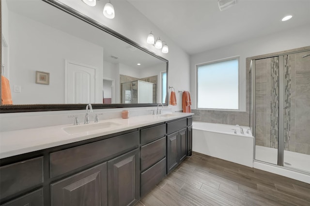 bathroom with double vanity, a stall shower, a garden tub, and a sink