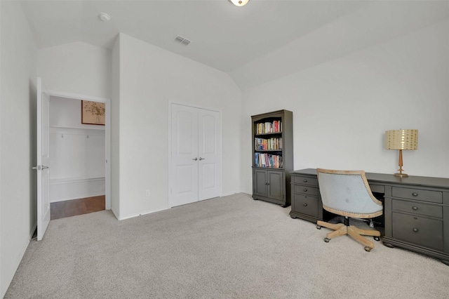 unfurnished office with carpet floors, visible vents, and vaulted ceiling