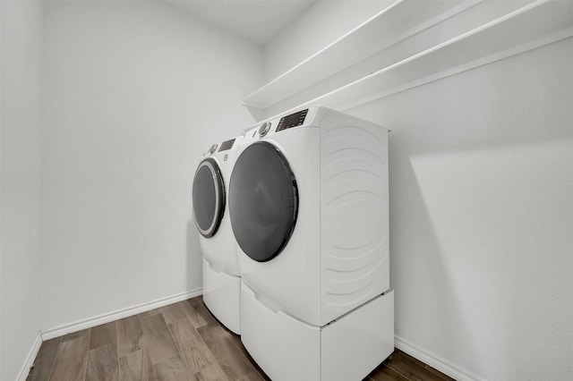 laundry area featuring laundry area, washing machine and dryer, baseboards, and dark wood-style flooring