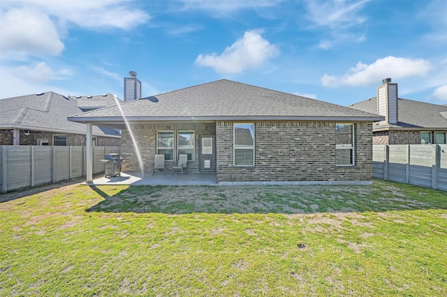 back of house featuring a patio area, a lawn, a fenced backyard, and brick siding