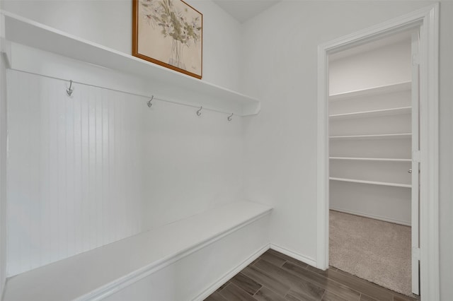 mudroom with dark wood finished floors and baseboards