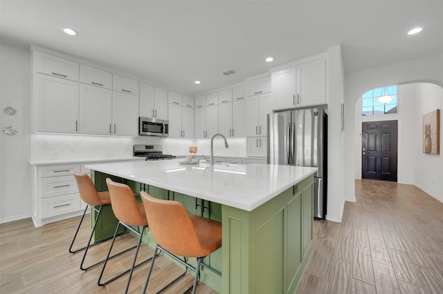 kitchen with appliances with stainless steel finishes, white cabinets, green cabinetry, and a sink