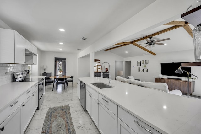 kitchen featuring appliances with stainless steel finishes, lofted ceiling with beams, backsplash, sink, and white cabinetry