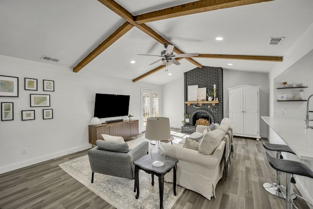 living room featuring a fireplace, hardwood / wood-style floors, vaulted ceiling with beams, and ceiling fan