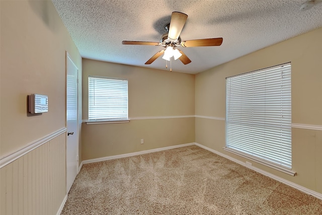 carpeted empty room with ceiling fan and a textured ceiling