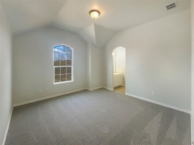 carpeted empty room with vaulted ceiling