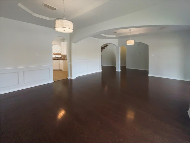 spare room featuring a raised ceiling, dark wood-type flooring, and sink