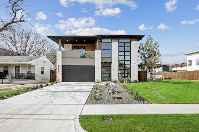 contemporary house with a front lawn, a garage, and a balcony