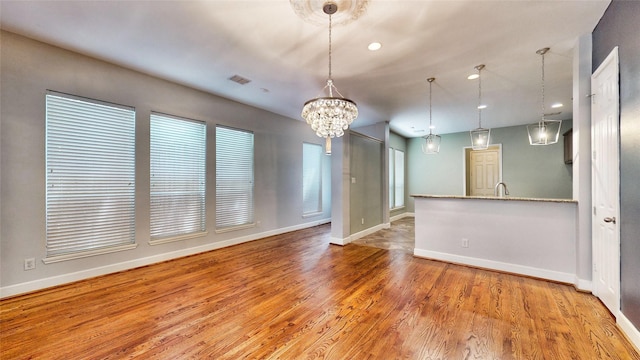 empty room with an inviting chandelier and hardwood / wood-style floors