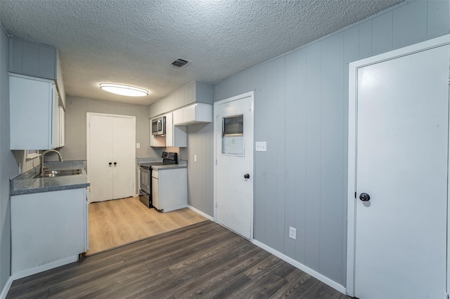 kitchen featuring dark wood-type flooring, a textured ceiling, white cabinets, sink, and black electric range oven