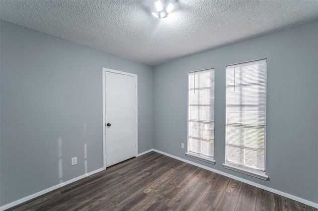 spare room featuring a textured ceiling and dark hardwood / wood-style flooring