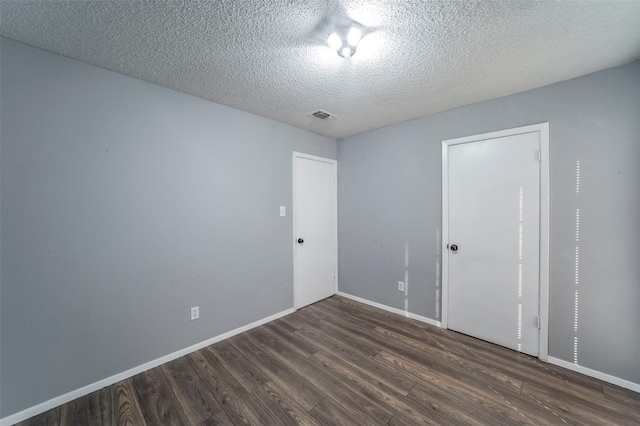 unfurnished room featuring a textured ceiling and dark wood-type flooring