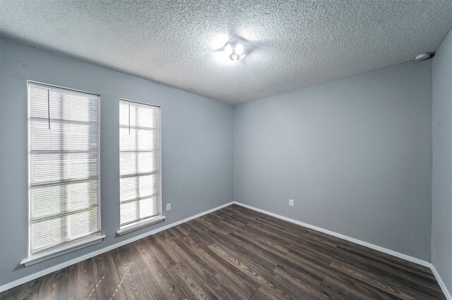 empty room featuring dark wood-type flooring and a textured ceiling