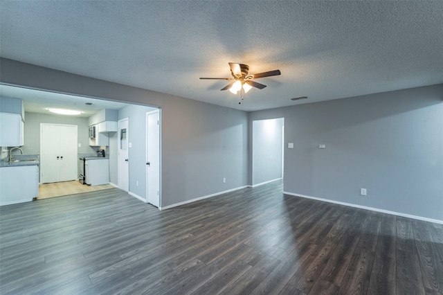 unfurnished living room with a textured ceiling, ceiling fan, dark hardwood / wood-style floors, and sink