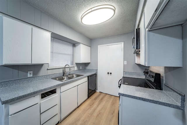 kitchen with sink, light wood-type flooring, a textured ceiling, black appliances, and white cabinets