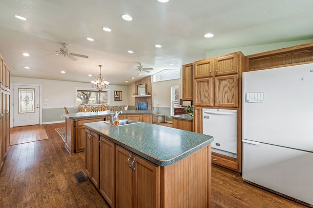 kitchen with white fridge, vaulted ceiling, sink, pendant lighting, and an island with sink