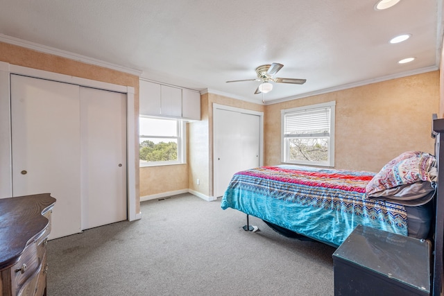 bedroom with carpet, ornamental molding, two closets, and ceiling fan