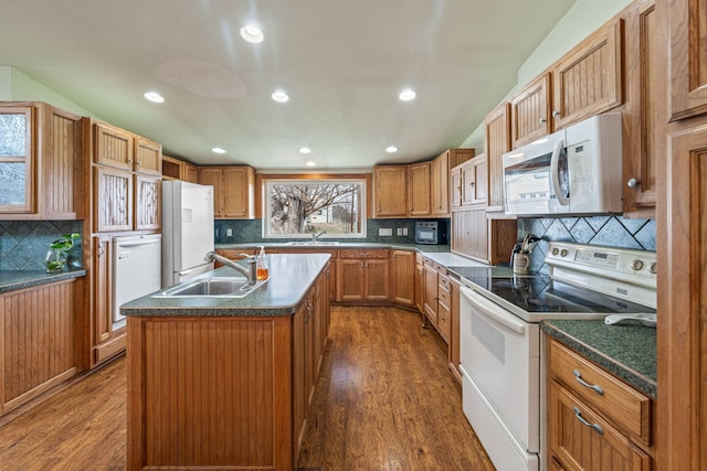 kitchen with sink, white appliances, an island with sink, and dark wood-type flooring