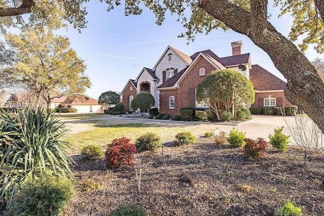 view of front of house with brick siding, a chimney, and a front yard