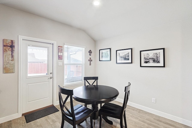 dining area with light wood-style floors, lofted ceiling, and baseboards