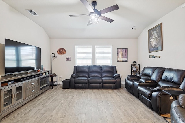 living room featuring ceiling fan, visible vents, baseboards, vaulted ceiling, and light wood finished floors