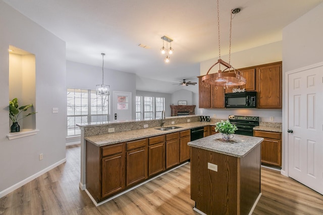 kitchen featuring pendant lighting, black appliances, a kitchen island, and kitchen peninsula