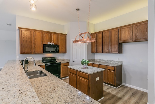 kitchen with sink, pendant lighting, black appliances, and light stone counters