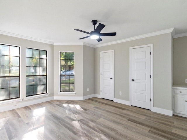 empty room with ceiling fan, light wood-type flooring, and crown molding